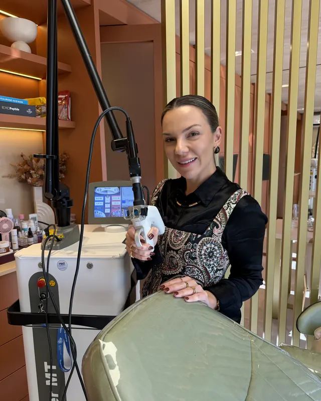 A Dra. Marina sorrindo ao lado do aparelho de laser de CO2 no consultório